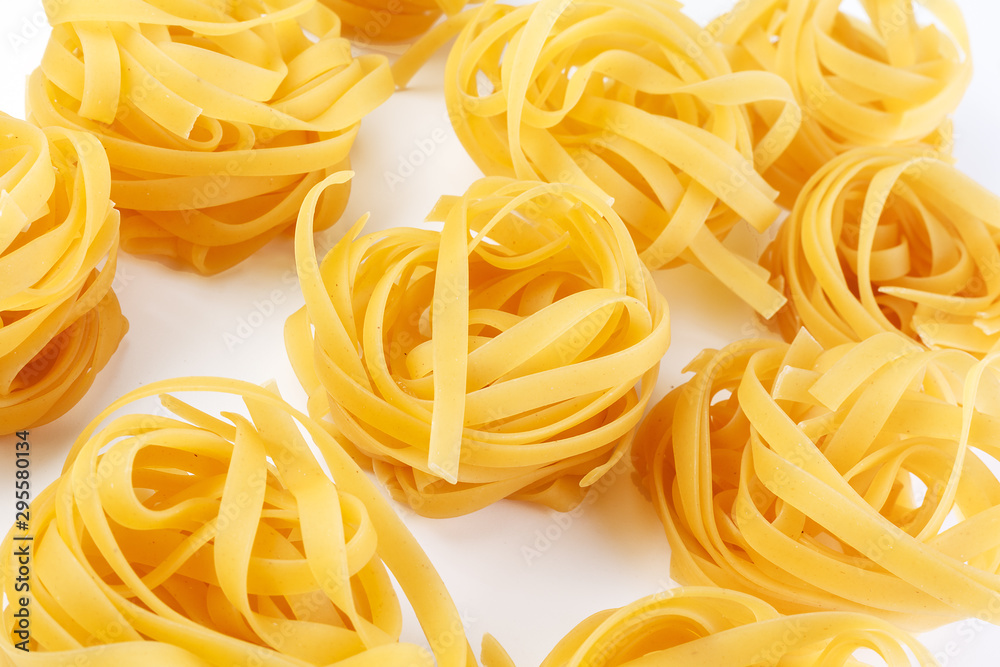 Italian rolled Raw noodles. Pasta on white background . Egg homemade dry ribbon noodles, long rolled macaroni or uncooked spaghetti isolated. Italian rolled Raw noodles. Pasta on white background . Egg homemade dry ribbon noodles, long rolled macaroni or uncooked spaghetti isolated.