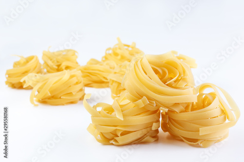 Italian rolled Raw noodles. Pasta on white background . Egg homemade dry ribbon noodles, long rolled macaroni or uncooked spaghetti isolated.