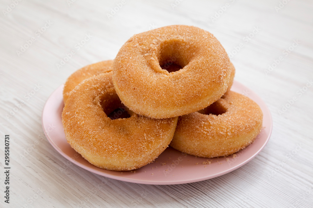 Homemade autumn apple donuts on a pink plate on a white wooden background, side view. Close-up.