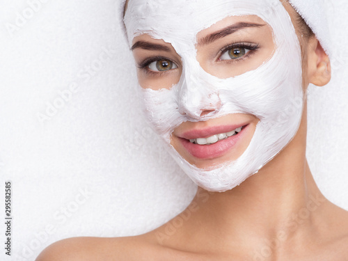 smiling woman in spa salon with cosmetic mask on face