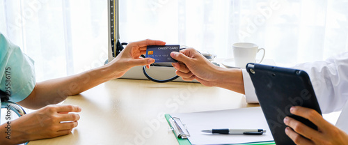 female patient receiving treatment and pay medical bills by credit card.