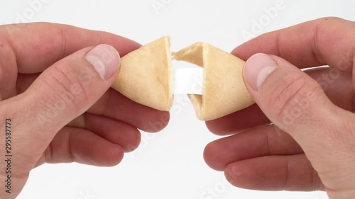 Close-up of male hands opening a fortune cookie with a card inside. Isolated, on white background.