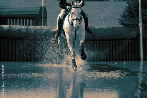 Horse and rider at a water jump competing, in the cross country stage, at an equestrian three day event. With colour toning photo