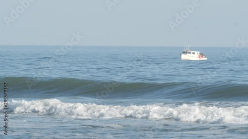Fishing boat in ocean by beach as birds fly by 4k - OBX Outer Banks HAtteras