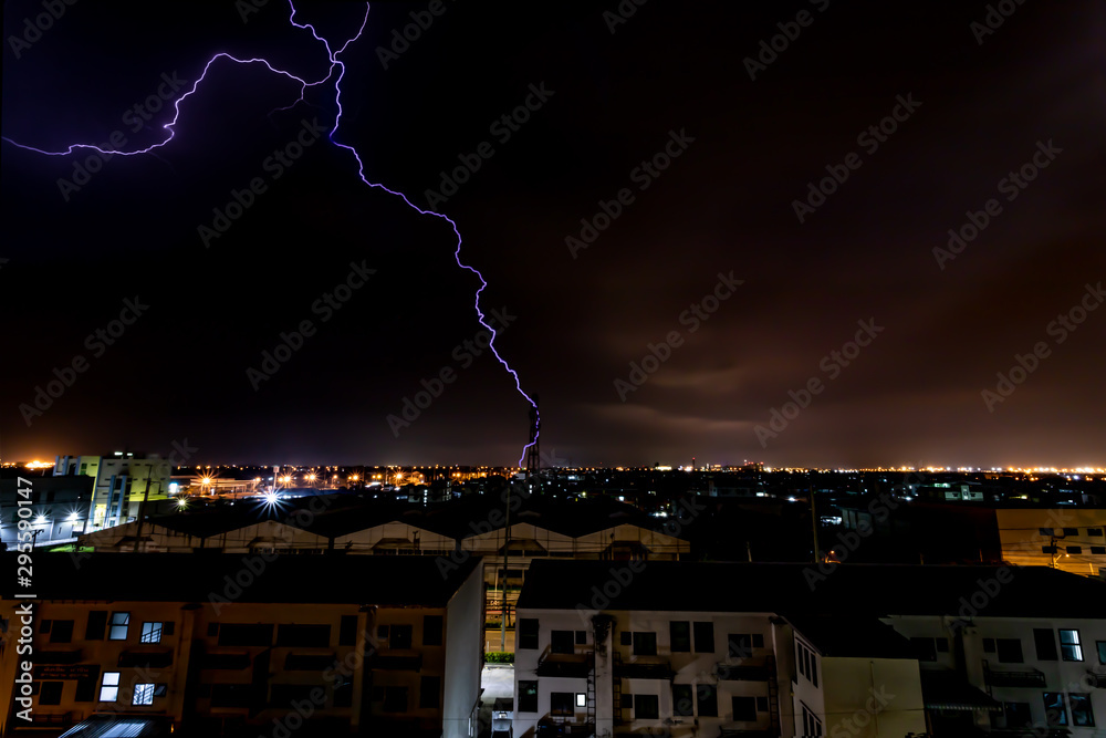 Lightning bolt strikes tower in industrial area at night.
