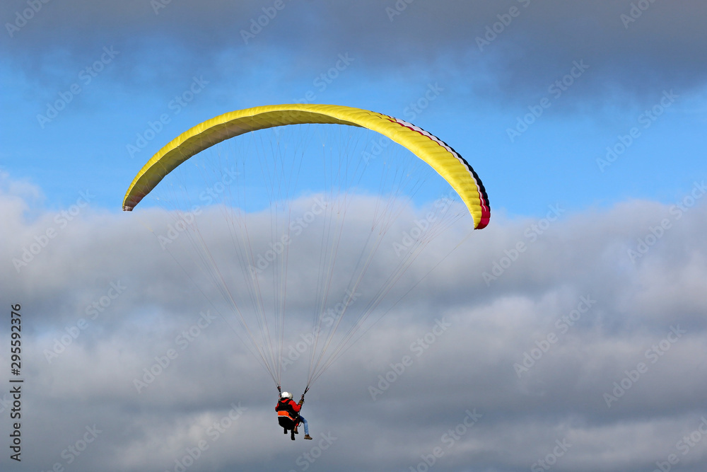 Tandem Paraglider flying wing in a blue sky Tandem Paraglider flying wing in a blue sky