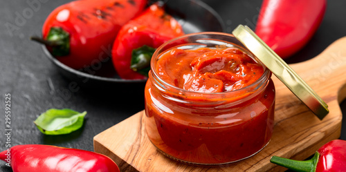 Grilled red pepper sauce (lutenica)  in glass jar with toasted bread. photo