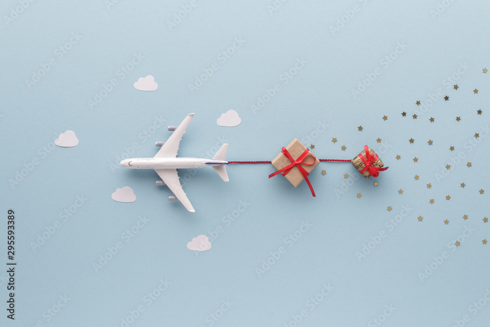 Fototapeta Christmas composition. Airplane flying in sky star gift clouds top view background with copy space for your text. Flat lay.