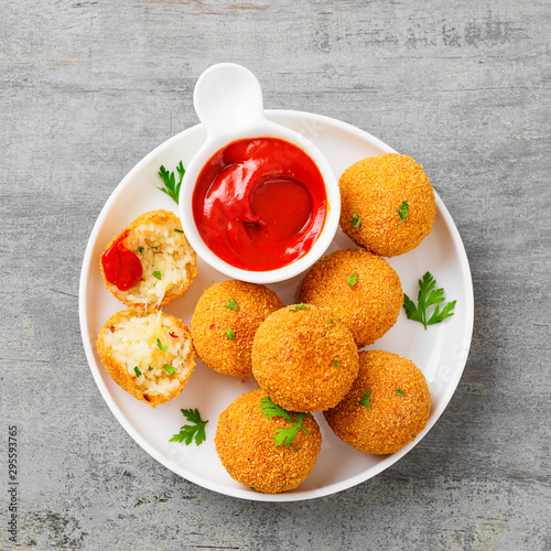 Homemade Fried Risotto Arancini stuffed with cheese, served with tomato sauce. photo