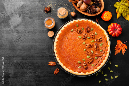 Festive Homemade Pumpkin Pie decorated with pecan nuts and pumpkin seeds.