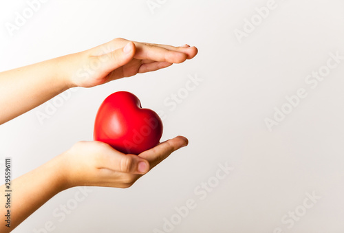 Fototapeta Naklejka Na Ścianę i Meble -  red heart in child's hands on light background