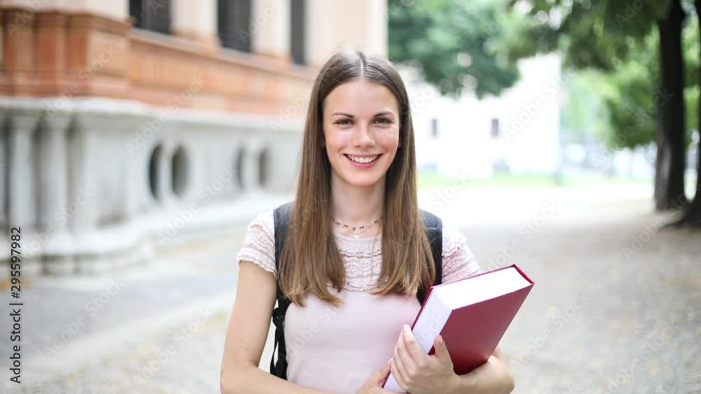 Female student holding walking outdoor in the park and smiling - slow motion Female student holding walking outdoor in the park and smiling - slow motion