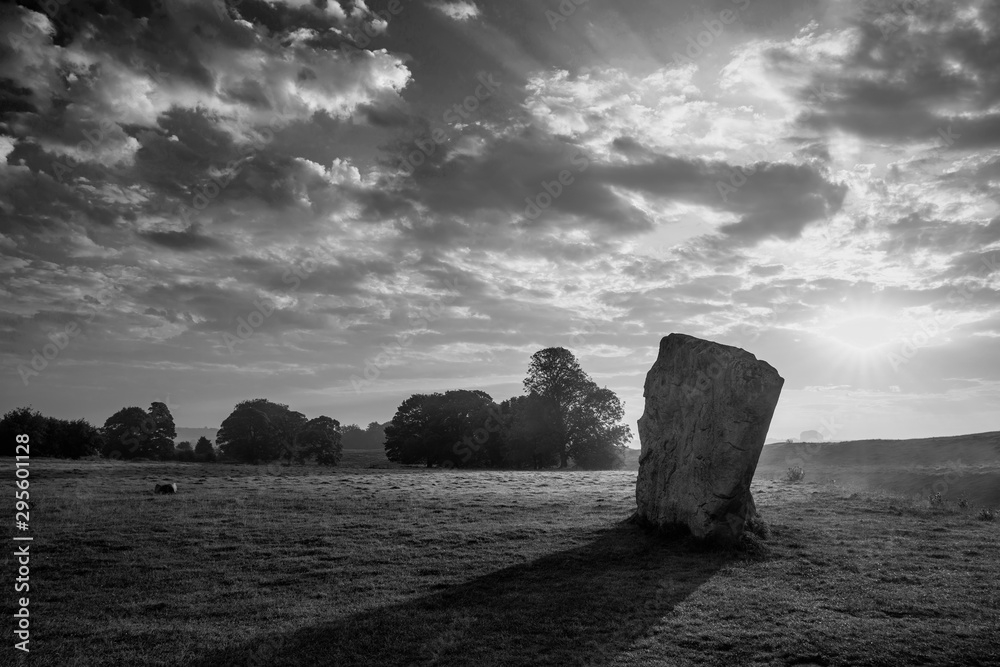 Stunning  black and white Summer sunrise landscape of Neolithic standing stones in English cluntryside with gorgeous light with slight background mist