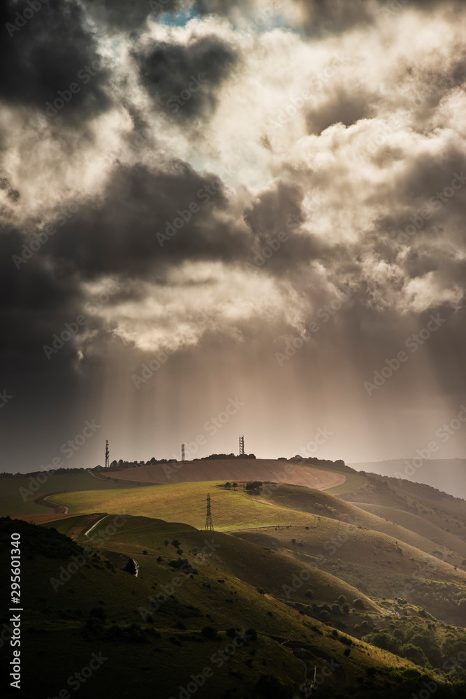 Stunning Summer landscape image of escarpment with dramatic storm clouds and sun beams streaming down