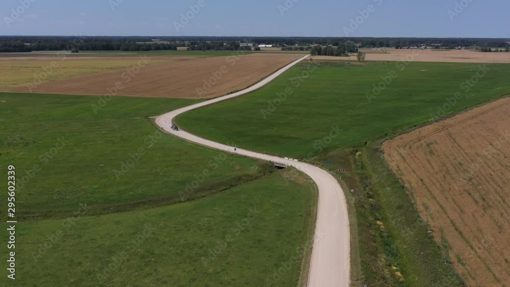 Agriculture tractor on beautiful white gravel road in summer, aerial view Agriculture tractor on beautiful white gravel road in summer, aerial view