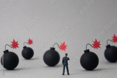 Multiple bombs and miniature businessman on grey background photo