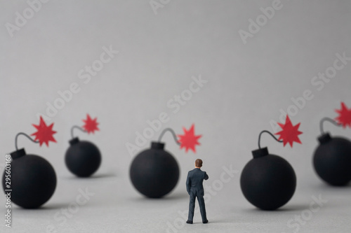 Multiple bombs and miniature businessman on grey background