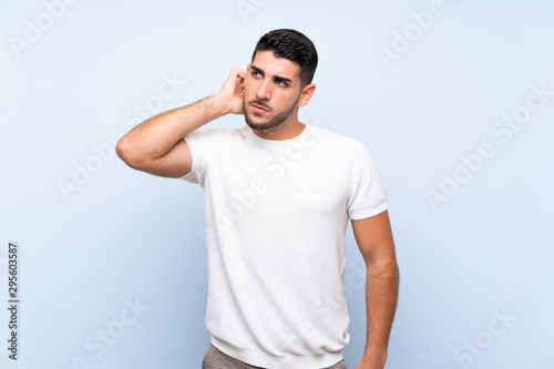 Caucasian handsome man over isolated blue background having doubts