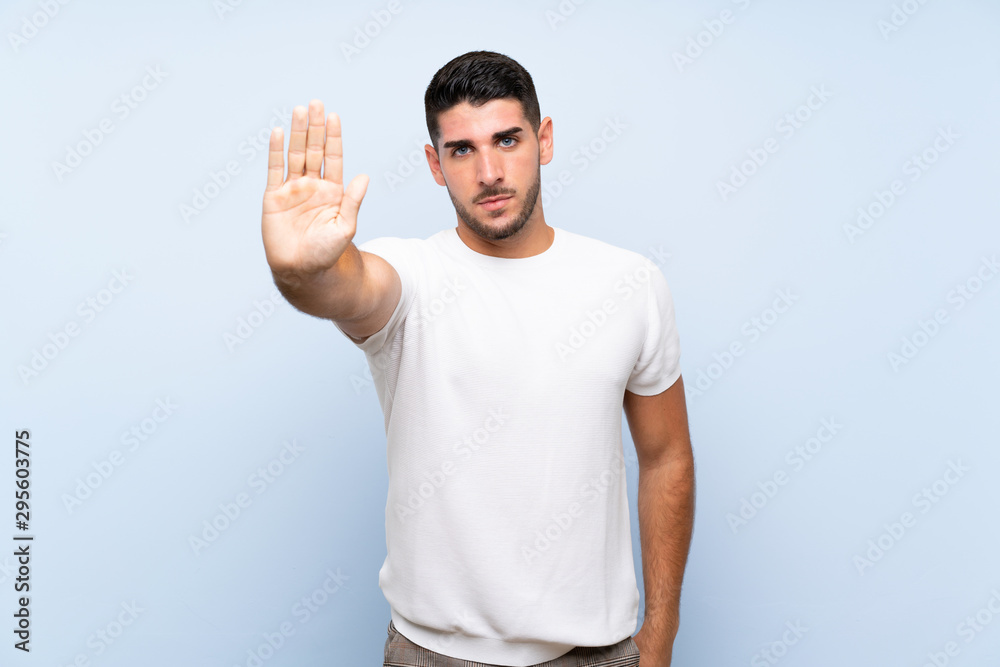 Caucasian handsome man over isolated blue background making stop gesture Caucasian handsome man over isolated blue background making stop gesture