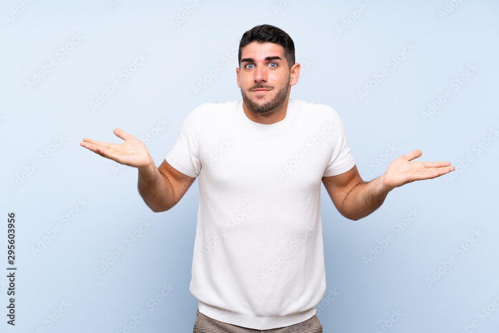 Caucasian handsome man over isolated blue background making doubts gesture Caucasian handsome man over isolated blue background making doubts gesture