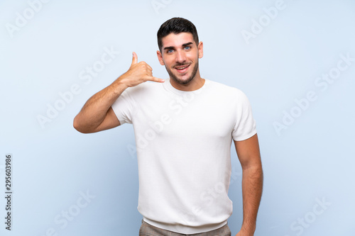 Caucasian handsome man over isolated blue background making phone gesture. Call me back sign