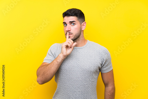 Young handsome man over isolated yellow background doing silence gesture
