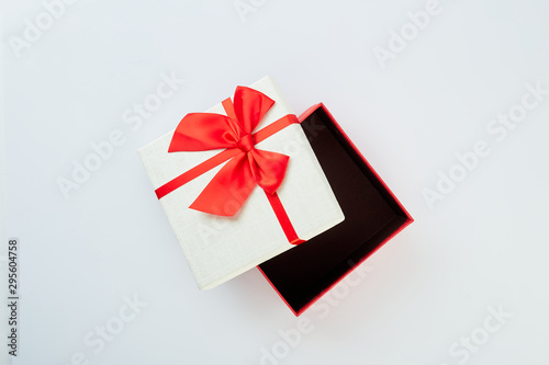 White gift box with red ribbon bow on white