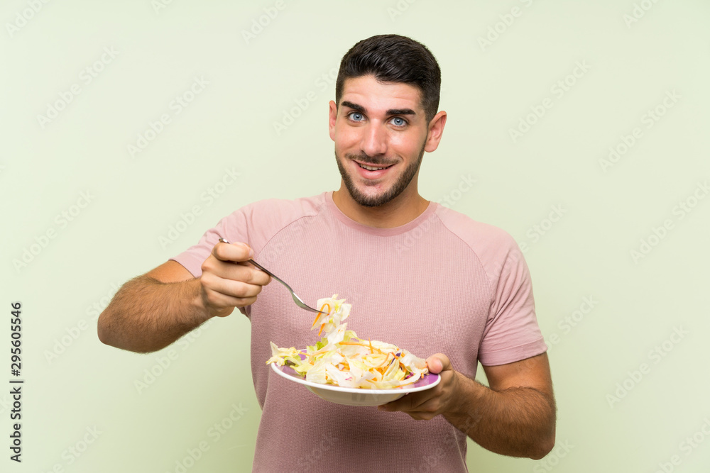 Young handsome man with salad over isolated green wall Young handsome man with salad over isolated green wall