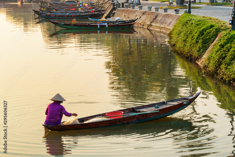 Vietnamese woman in traditional bamboo hat on wooden boat, Hoian