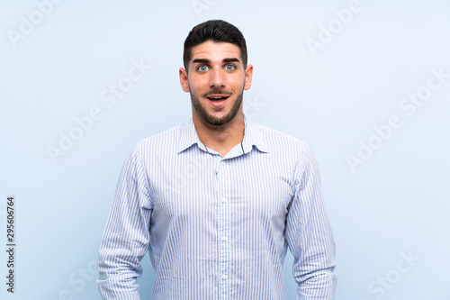 Caucasian handsome man over isolated blue background with surprise facial expression