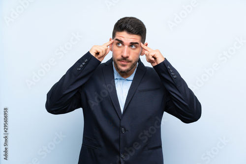 Handsome man over isolated blue background having doubts and thinking