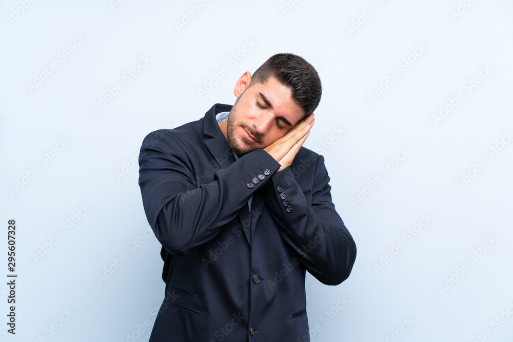 Handsome man over isolated blue background making sleep gesture in dorable expression Handsome man over isolated blue background making sleep gesture in dorable expression