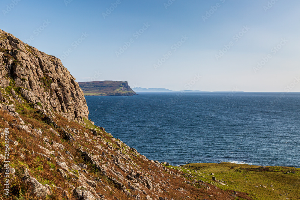 The coastline at Neist Point on the western side of the Isle of Skye, with a blue sky overhead