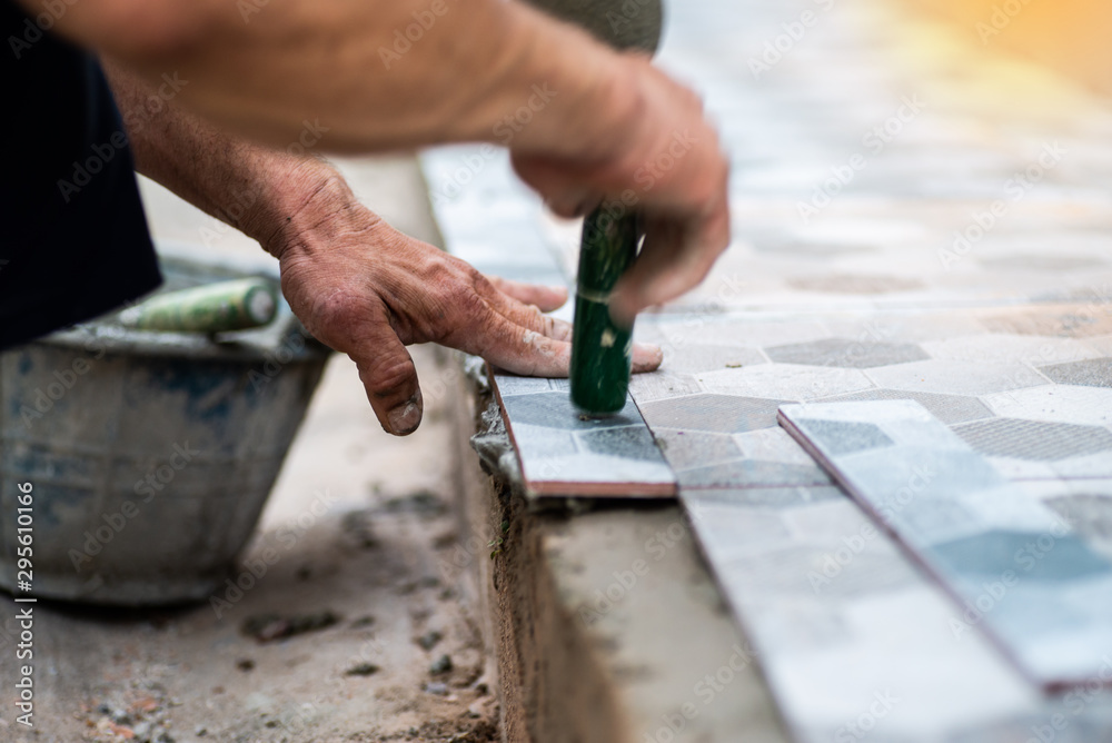 Close up of handyman affixing adhesive grout to get tiled concrete before the front door. Close up of handyman affixing adhesive grout to get tiled concrete before the front door.