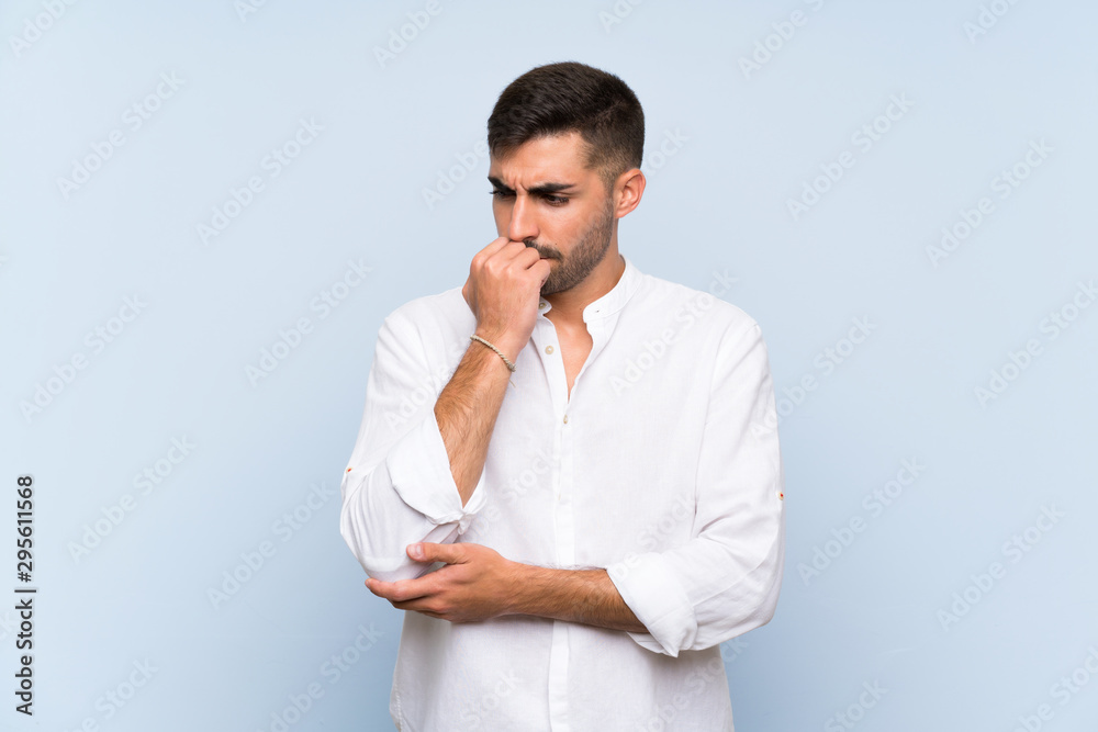 Handsome man with beard over isolated blue background having doubts