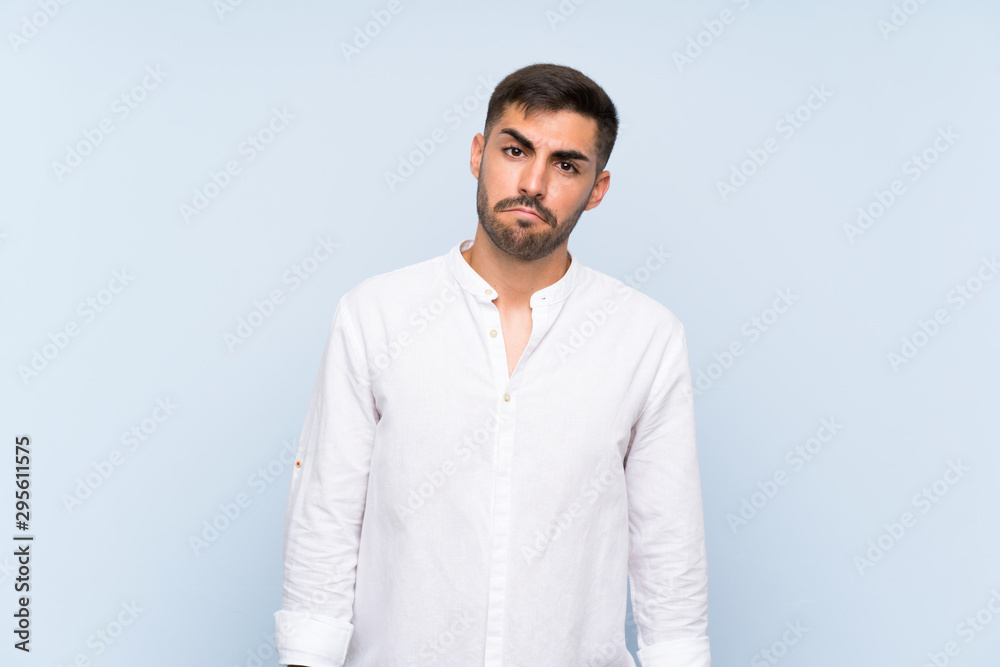 Handsome man with beard over isolated blue background with sad and depressed expression Handsome man with beard over isolated blue background with sad and depressed expression