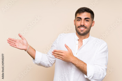 Handsome man with beard over isolated background extending hands to the side for inviting to come