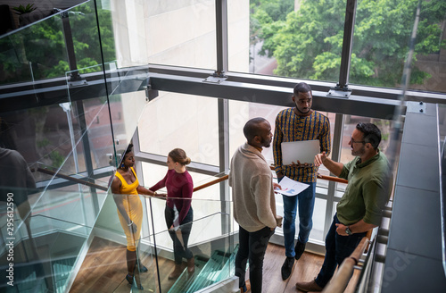 Diverse group of creative business people casually talking on office stairwell before meeting