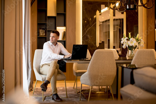 Business man sitting in a luxurious room in front of a laptop photo