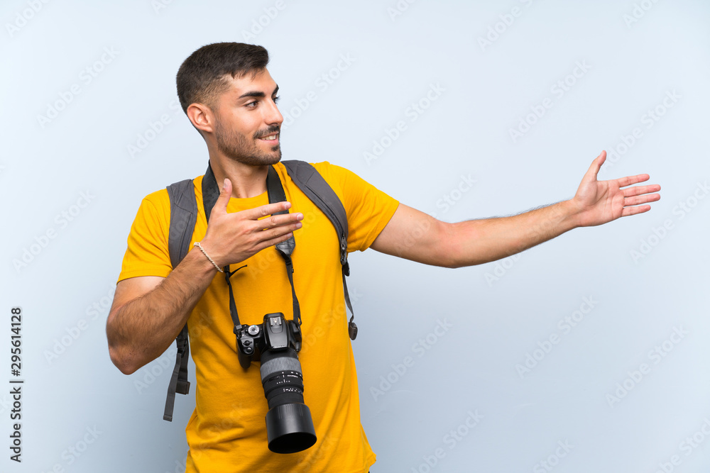 Young photographer man extending hands to the side for inviting to come Young photographer man extending hands to the side for inviting to come