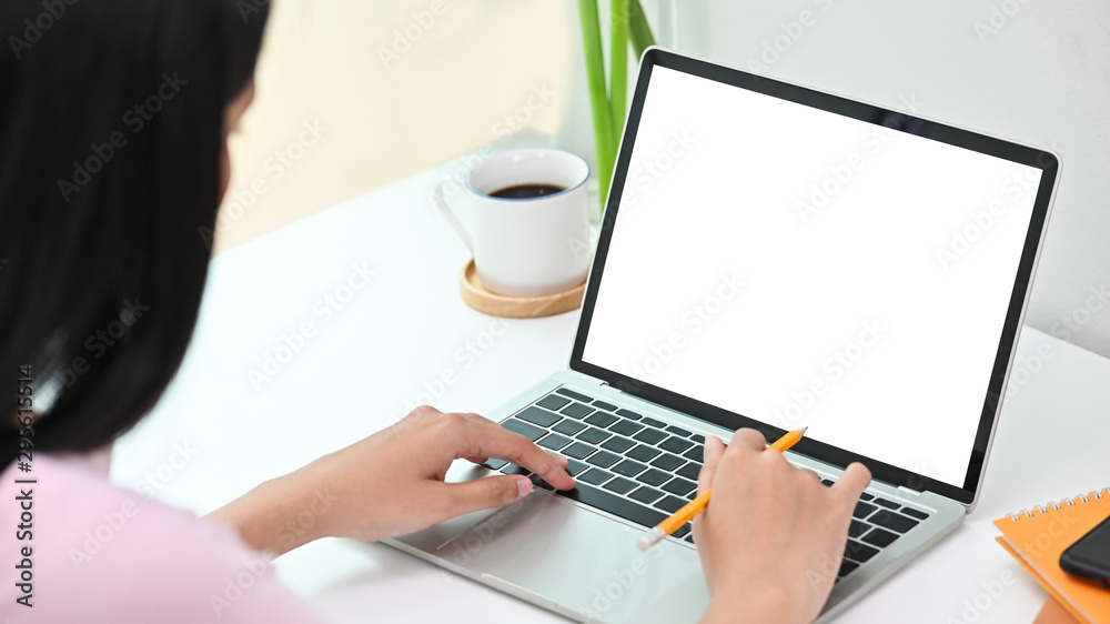 Woman using laptop computer with blank screen in creative workspace. Woman using laptop computer with blank screen in creative workspace.