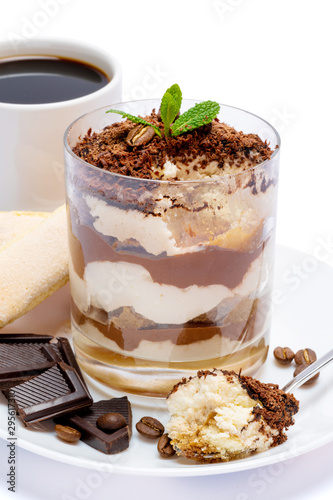 Classic tiramisu dessert in a glass, cup of coffee and pieces of chocolate on white background with clipping path