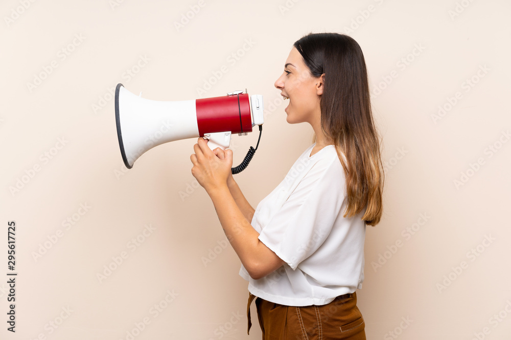 Young brunette woman over isolated background shouting through a megaphone Young brunette woman over isolated background shouting through a megaphone