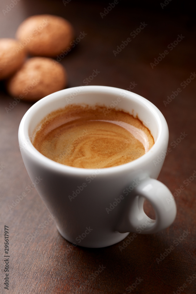 Cup of coffee with amaretti (Italian biscuits) on rustic wooden background. Close up.