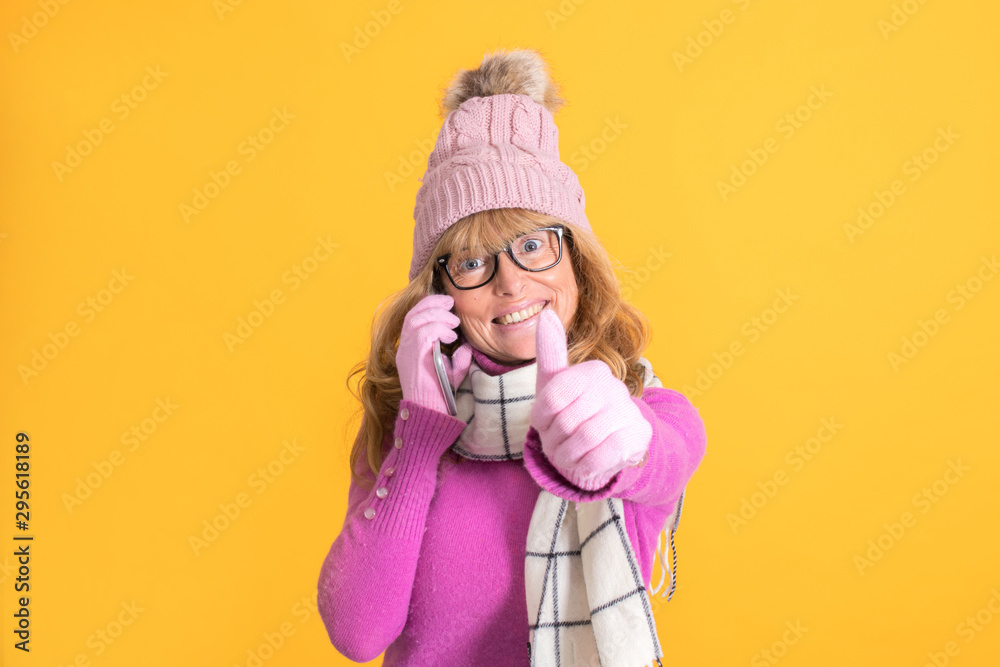 warm woman with winter clothes talking on the phone isolated on color background warm woman with winter clothes talking on the phone isolated on color background