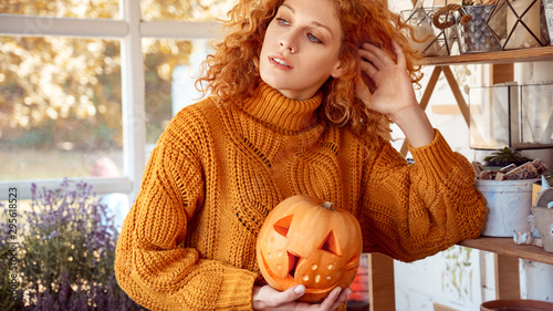 Bild auf Leinwand Woman holding carved pumpkin, preparing halloween celebration at home