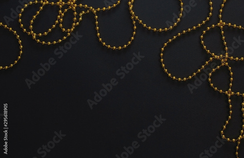 Gold Christmas garland on a black background. Top view. Copy space.Christmas frame for text. Black Christmas background with lights and bokeh.