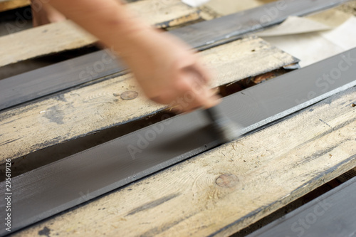 Painting boards with a brush held in hand. Gray, anthracite wood paint.