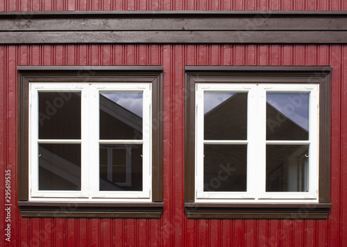 Burgundy facade with two white windows and a beam above them.