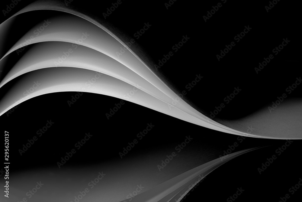 curved white sheets of paper against a dark background - obrazy, fototapety, plakaty 